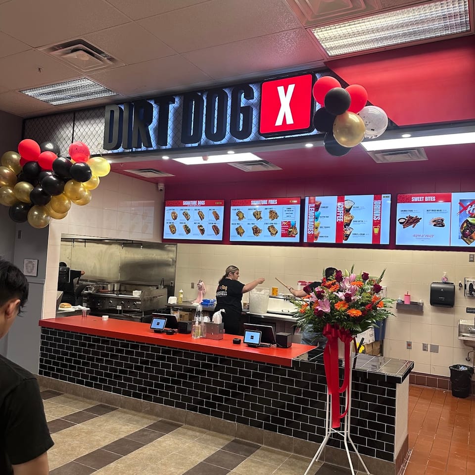 Dirt Dog X restaurant interior with menu boards, counter, kitchen, and staff preparing food.