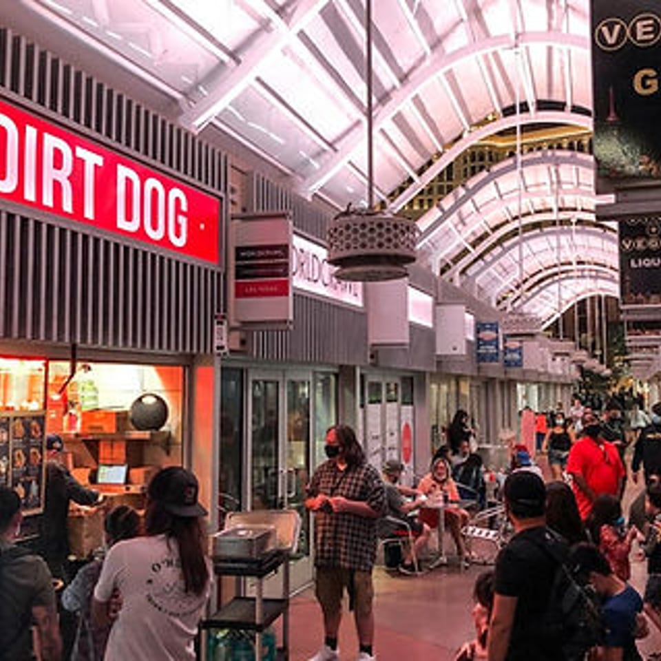 Dirt Dog restaurant with a bright red sign, bustling with customers in a lively indoor market.