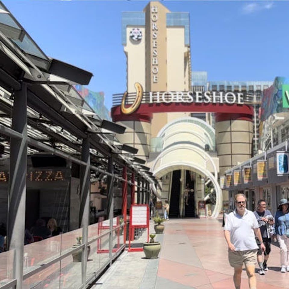 People walk past outdoor dining and shops with the Horseshoe casino in the background.